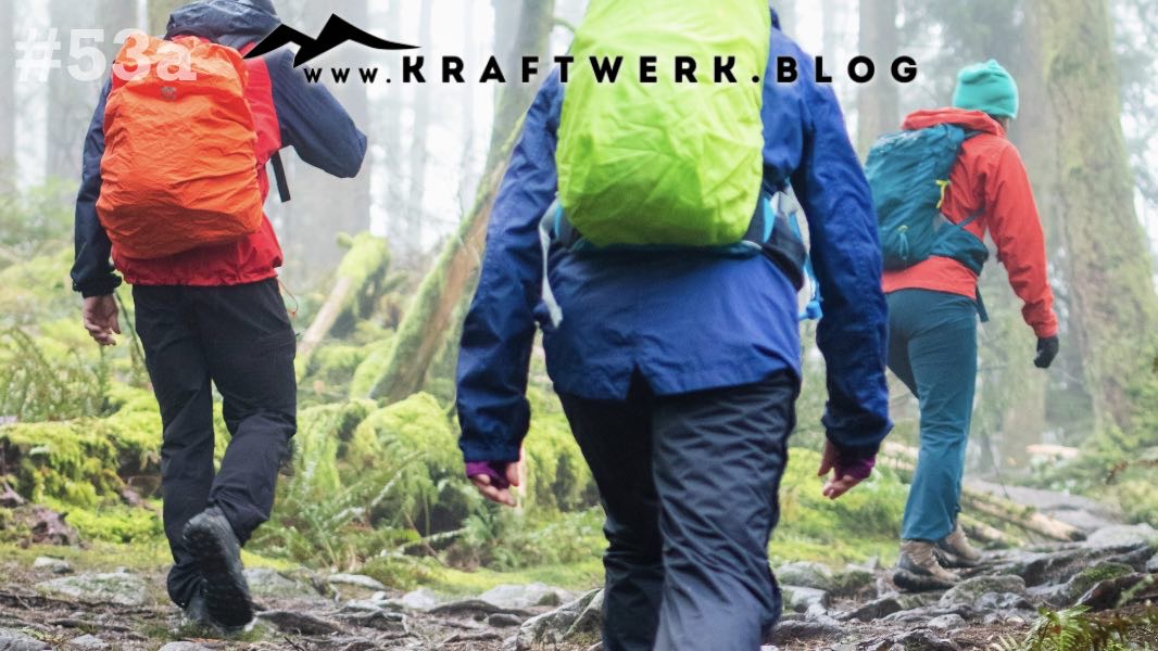 Drei Wanderer im Wald, bekleidet mit Regenkleidung ziehen sie durch das leicht neblige Unterholz. Titelbild zum Post „Gemeinsam unterwegs“ auf dem www.kraftwerk.blog #53a
